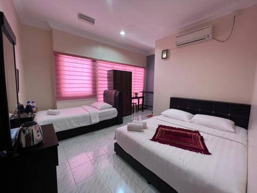克提HOTEL RAUDHAH Kerteh的酒店客房设有两张床和窗户。