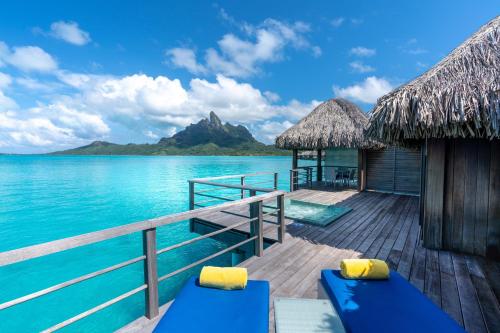波拉波拉博拉博拉岛瑞吉度假酒店的一个带蓝色长椅和水的度假甲板