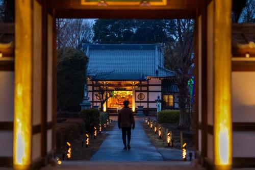 ChiyodamachiTEMPLESTAY ZENSŌ的一个人在花园中沿着人行道走,