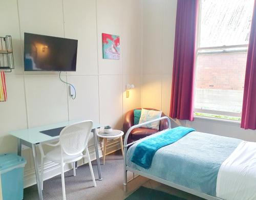 但尼丁Extended Stay City Hostel的一间卧室配有一张床、一张桌子和一张书桌