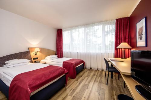 纽伦堡阿维娜会展中心酒店的酒店客房设有两张床、一张桌子和一台电视。