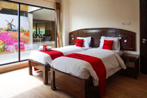 MadandanRedDoorz near Londa Toraja的一间卧室配有两张带红色枕头的床和窗户。