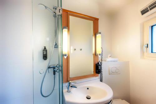 杜塞尔多夫B&B Hotel Düsseldorf-Hbf的浴室配有盥洗盆和带镜子的淋浴