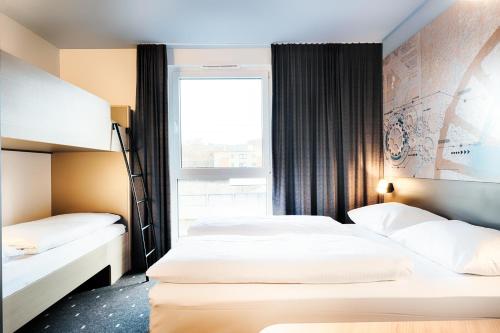 波鸿B&B Hotel Bochum-City的配有窗户的酒店客房内的两张床
