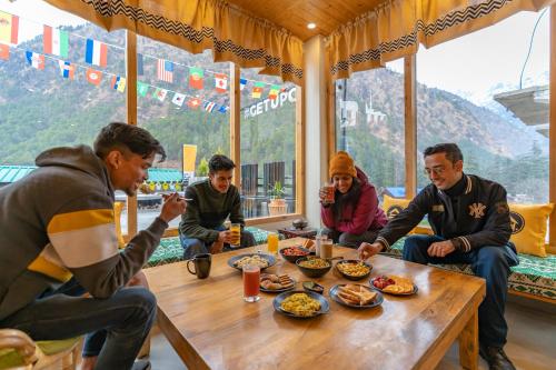 卡索尔The Hosteller Kasol, Parvati Valley的一群坐在桌子旁吃食物的人