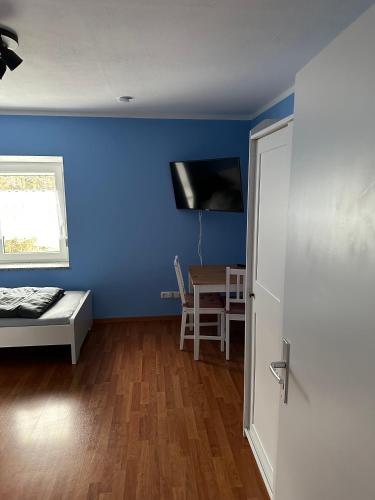 梅明根Apartment - Wohnung Memmingen Nr. 3的一间设有蓝色墙壁、一张床和一张桌子的房间