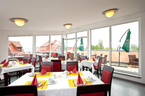 瓦伦慕特兹佩勒酒店的餐厅设有白色桌子和红色椅子,窗户