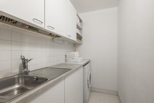 赫尔辛基Comfortable city home的一个带水槽和白色橱柜的小厨房