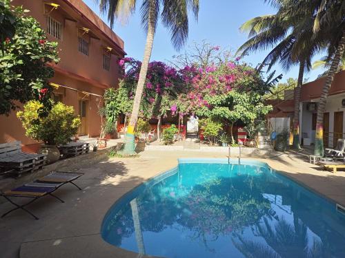 姆布尔Guesthouse Dalal ak Jàmm的棕榈树建筑前的游泳池