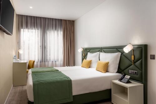 里斯本Empire Marquês Hotel的酒店客房配有一张带黄色枕头的大床