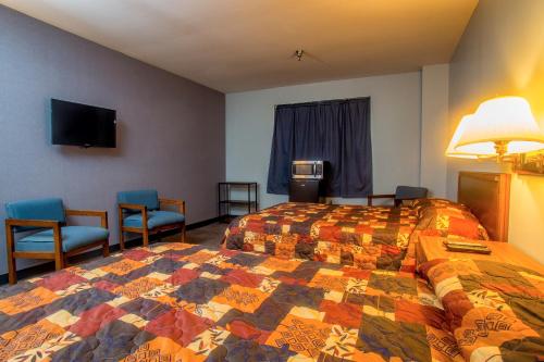 MoundsvilleLafayette Inn的酒店客房,配有一张床和两把椅子