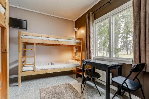 Lärbro莱尔布鲁/格兰内恩STF旅馆的一间卧室配有双层床、一张桌子和一个窗户。
