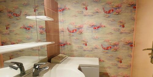 滨海卡约Studio lumineux face mer à Cayeux sur mer的一间带水槽的浴室和一张粉红色的壁纸