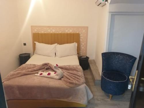 马拉喀什Hôtel Agnaou的一间卧室配有一张带毯子和椅子的床