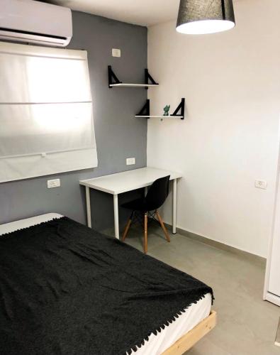 贝尔谢巴Pninat Hadrom的一间卧室配有一张床、一张书桌和一个窗户。