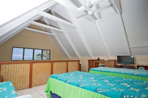 拉罗汤加白沙滩别墅的一间带两张床的卧室和一台电视