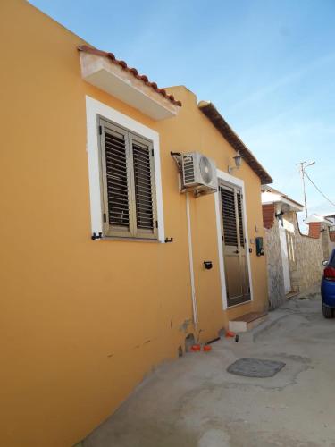 兰佩杜萨Villa Ale的黄色的房屋,设有窗户和风扇