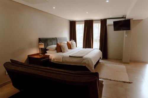 RietfonteinMarjaniek Wedding Venue & Guest House的一间卧室配有一张床、一台电视和一张沙发