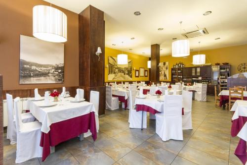 阿拉力兹阿拉里克餐厅旅馆的餐厅设有白色的桌椅和吊灯。