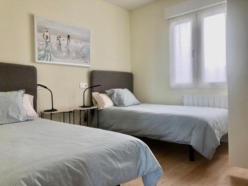 希洪SUITE PLAYA GIJON CENTRO, apartamento nuevo, 5 huéspedes VUT-3622-AS的一间卧室设有两张床和窗户。