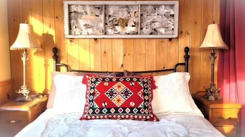 Saint-FulgenceLa vieille ferme, Écogîte的一间卧室配有一张带红色枕头和两盏灯的床