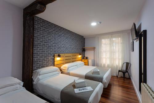 毕尔巴鄂Casual Mardones的酒店客房带两张床和砖墙