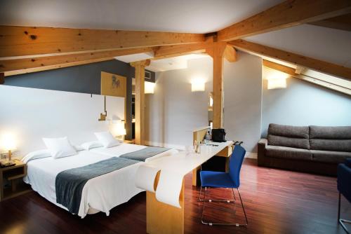 巴利亚多利德泽尼特科勒奇奥旅馆的一间卧室配有一张床、一张桌子和一张沙发