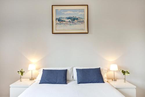 巴塞罗那瓦莱塔旅馆的一张带蓝色枕头的白色床和墙上的照片