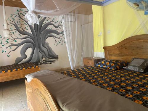 ToubakoutaLa kora的卧室配有一张墙壁上涂有树的床铺。