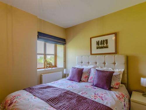 什鲁斯伯里Stone Cottage的一间卧室配有一张带紫色枕头的大床
