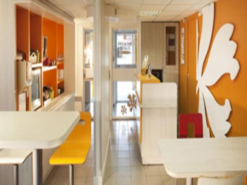 莫内托普瑞米尔奥克斯尔经典酒店的厨房拥有橙色的墙壁和白色的桌椅