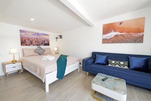 帕克德尔Beachside Compact Backyard Cabin near Mentone的一间卧室配有一张床和一张蓝色的沙发