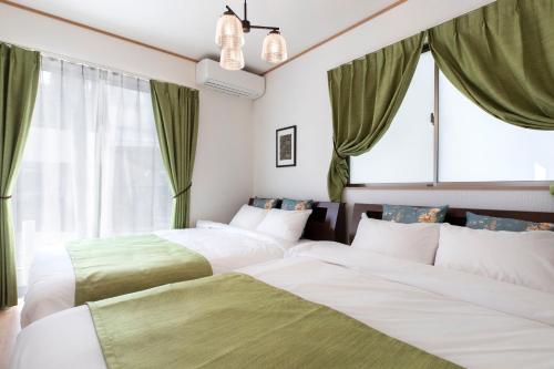 恩纳Y's沖縄リゾートベースNo.1的绿窗帘间内的两张床