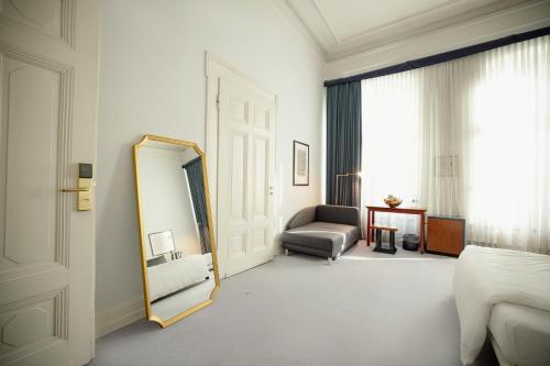 波恩Domicil Hotel Bonn的一间设有镜子、一张床和椅子的房间