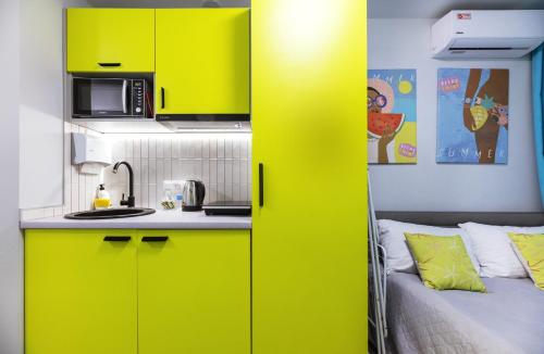 基辅MYFREEDOM Апартаменти метро Святошин的一间厨房,配有黄色橱柜和一张位于客房内的床