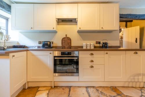 温什科姆Stunning 2 Bed Cotswold Cottage Winchcombe的厨房配有白色橱柜和烤箱。