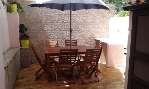 马达莱纳Villetta a schiera的一张带椅子的木桌和一把伞