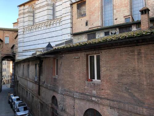 锡耶纳Alla Scala 1746的路边的砖砌建筑,有汽车停放