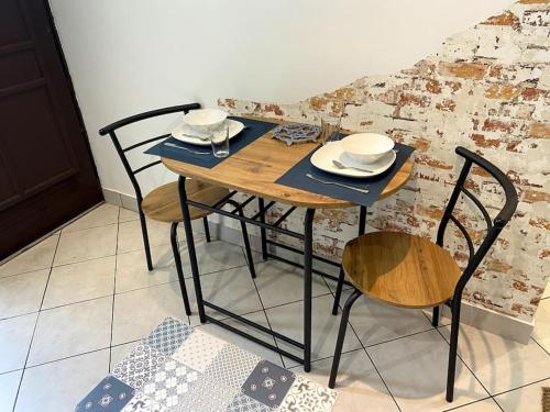 蒙雷里studio le 17 près de Paris的一张木桌,上面有椅子和盘子