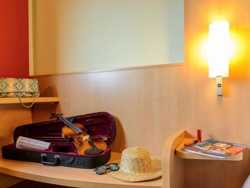 卡尔达诺阿尔坎波米兰马尔彭萨宜必思酒店的手提箱,坐在桌子上,戴帽子,小提琴