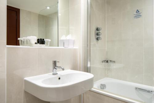 伦敦丹乌比斯摄政公园酒店的白色的浴室设有水槽和淋浴。