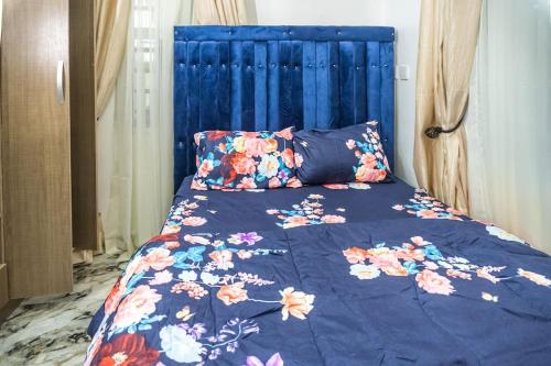 拉各斯Adorable 1-Bedroom-Apt With 24hrs Electricity & Unlimited Internet的一张带蓝色床头板的床上,上面有鲜花