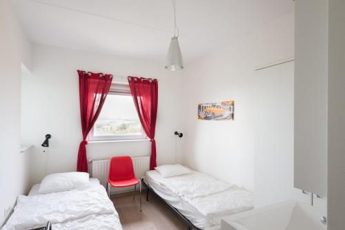 布雷斯肯斯Hello Zeeland - Appartement Port Scaldis 19-042的一间设有两张床和红色椅子的房间