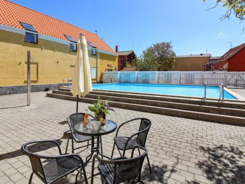 古兹耶姆Apartment Thyrne - 500m from the sea in Bornholm by Interhome的游泳池前配有桌椅和遮阳伞