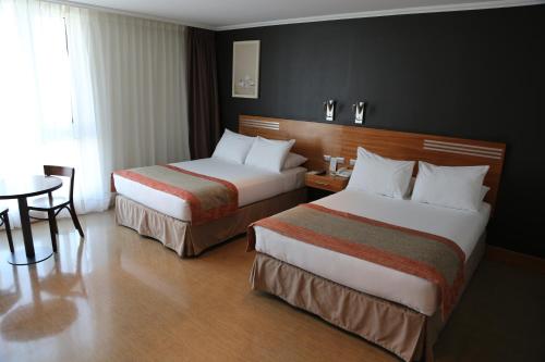 梅希约内斯Alto del Sol Latorre Mejillones的酒店客房设有两张床和一张桌子。
