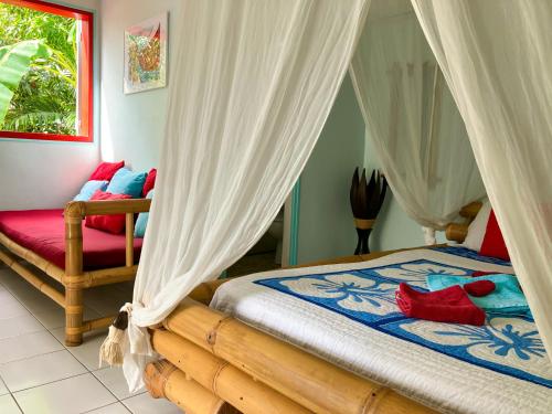 圣安尼Gîte Zandoli Koko的一间卧室配有带白色窗帘和红色枕头的床。
