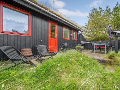 博利尔马克Holiday Home Kathaline - 3-4km from the sea in Western Jutland by Interhome的黑色的房子,设有红色的门和椅子以及桌子