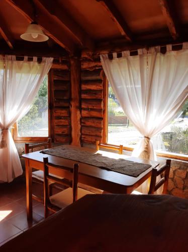 埃斯克尔Cabaña Pampa的一间设有桌子和两个窗户的房间