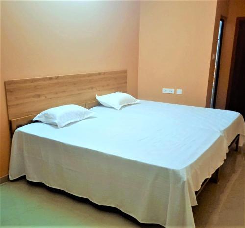 RānīSKR Gusto Inn的卧室配有一张带两个枕头的大白色床