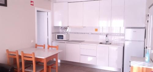 阿尔沃尔Casa Alvor - a criar Memórias的厨房配有白色橱柜和桌椅
